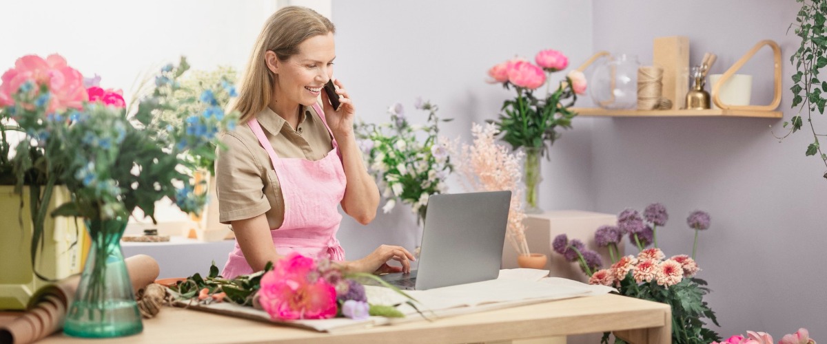 Kukkakaupan yrittäjä puhelimessa asiakkaan kanssa