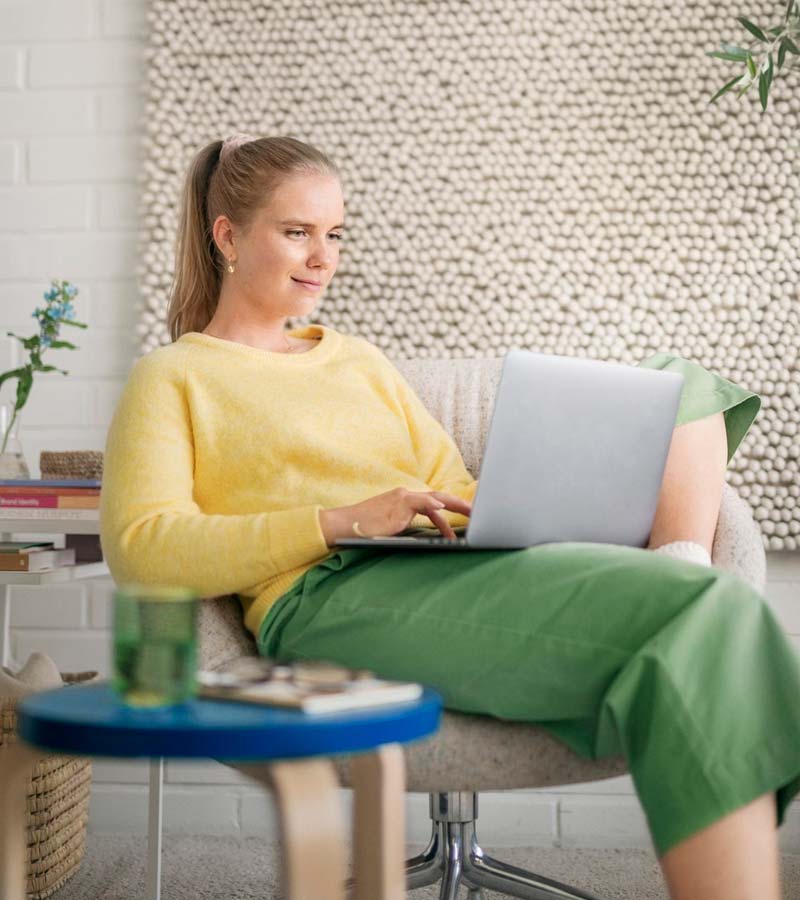 Nainen istumassa kotona kannettava tietokone sylissä